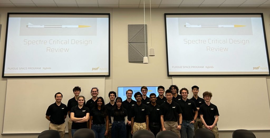 HY Spectre CDR team photo A group of students stand together below screens reading "Spectre Critical Design Review"
