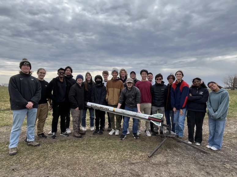 Spaceport Prometheus launch team photo A group of students stand in a field folding a white rocket horizontally