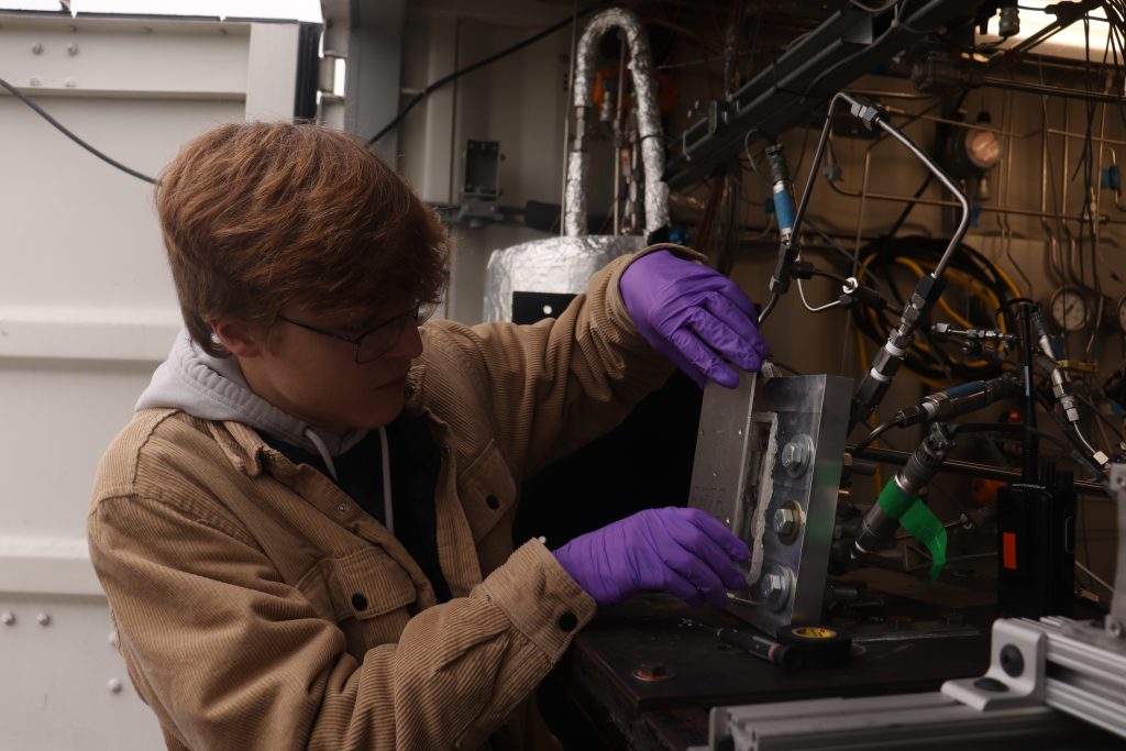AC purple gloves A student wearing purple gloves works on fluid systems for a rocket